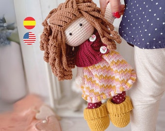 May include: A crocheted doll with brown hair, a pink and yellow plaid dress, a burgundy sweater, and brown shoes.
