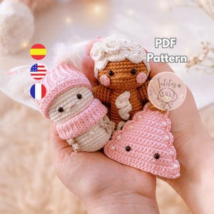 May include: A collection of handmade crochet ornaments, including a gingerbread person, a snowman, and a Christmas tree. The ornaments are in shades of brown, pink, and white. The image includes the text "PDF Pattern".