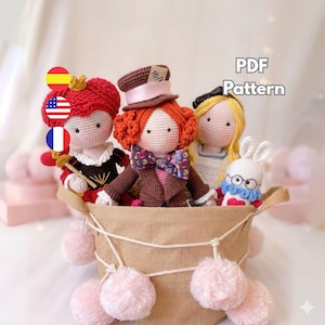 Könnte beinhalten: Gehäkelte Puppen, die Charaktere aus Alice im Wunderland darstellen, darunter die Herzkönigin, der Hutmacher, Alice und das weiße Kaninchen. Sie befinden sich in einem geflochtenen Korb mit rosa Pompons. Der Text "PDF Pattern" ist enthalten.