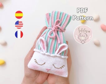 Könnte beinhalten: Eine handgefertigte Häkeltasche in Weiß, Rosa und Mintgrün. Die Tasche hat Hasenohren und ein gesticktes Gesicht. Die Oberseite ist mit einer rosa Schnur gebunden. Die Worte "PDF Pattern" sind sichtbar.