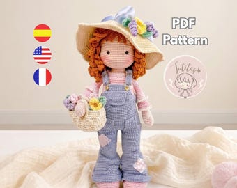 May include: A crochet doll with curly orange hair wearing a wide-brimmed straw-colored hat adorned with purple and yellow flowers, a pink long-sleeve shirt, and blue overalls. The doll holds a small woven basket filled with colorful flowers. Text reads PDF Pattern.