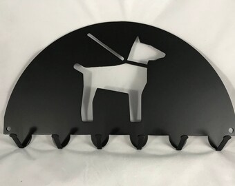 May include: Black metal key holder shaped like a half-circle with a dog silhouette cut out. The key holder has six hooks.