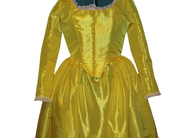 May include: A yellow satin dress with a fitted bodice and a full skirt. The dress has a lace trim around the neckline and cuffs.