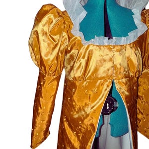 May include: A gold brocade dress with a white lace collar and long sleeves. The dress has a fitted bodice and a flowing skirt. The dress is on a mannequin.