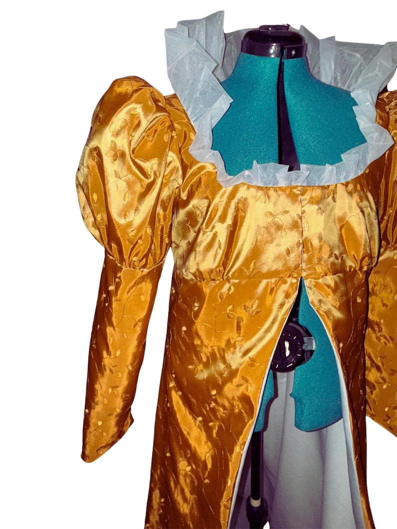 May include: A gold brocade dress with a white lace collar and long sleeves. The dress has a fitted bodice and a flowing skirt. The dress is on a mannequin.