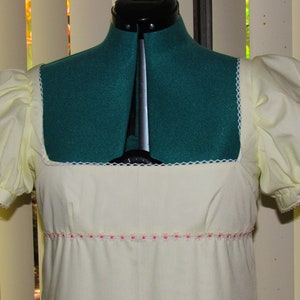 May include: A white dress with puffed sleeves and a square neckline. The dress has a pink trim around the waist.