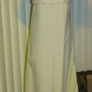 May include: A white, long-sleeved dress with puffed sleeves and a lace trim around the neckline. The dress has a simple, elegant design.