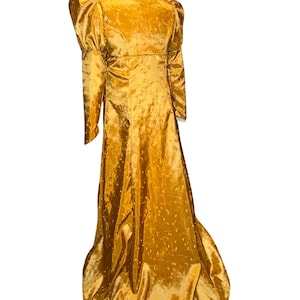 May include: A long, golden yellow gown with a high neckline and puffed sleeves. The gown has a subtle pattern of small dots and is made of a shiny fabric.