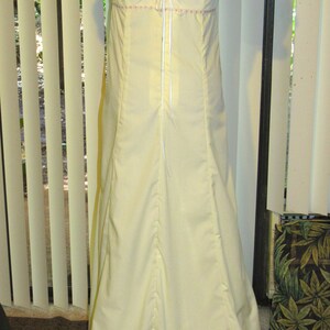 May include: A pale yellow maxi dress with a lace-up back and a gathered skirt. The dress has short sleeves and a round neckline.