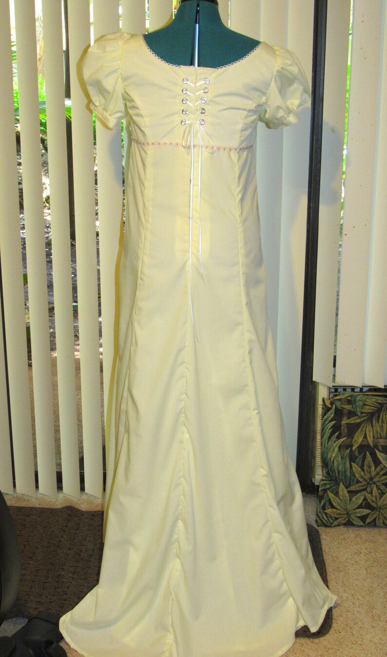 May include: A pale yellow maxi dress with a lace-up back and a gathered skirt. The dress has short sleeves and a round neckline.
