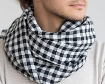 Könnte beinhalten: Ein Mann trägt einen weißen Pullover mit einem schwarz-weiß karierten Schal um den Hals. Er hat ein Tattoo auf seinem Arm.
