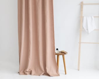 May include: A light pink linen shower curtain hangs from a silver rod. A wooden ladder with a white towel hanging on it is in the background.
