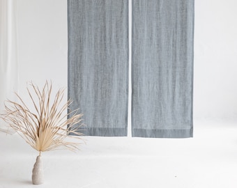 Puede incluir: Un par de cortinas de lino azul claro con una textura sutil colgando de una barra blanca contra una pared blanca.