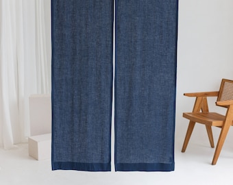 Puede incluir: Un par de cortinas de lino azul oscuro con un borde azul oscuro que cuelgan de una varilla blanca. Las cortinas están en una habitación minimalista con una silla blanca y un jarrón blanco.
