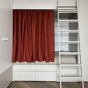 May include: A built-in bunk bed with a rust-colored curtain, white ladder, and storage drawers. The bed is nestled within a white-painted alcove, with a wooden herringbone floor.
