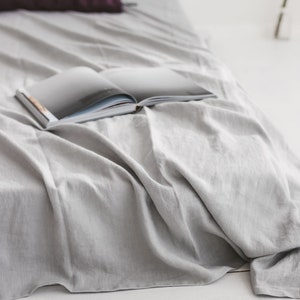 Peut inclure: Un couvre-lit en lin gris avec un livre ouvert dessus. Le livre est ferm&eacute; et a une couverture blanche.