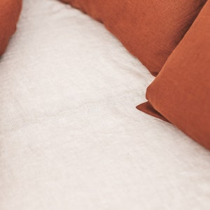 Peut inclure: Deux taies d'oreiller en lin de couleur rouille sur un drap en lin blanc.