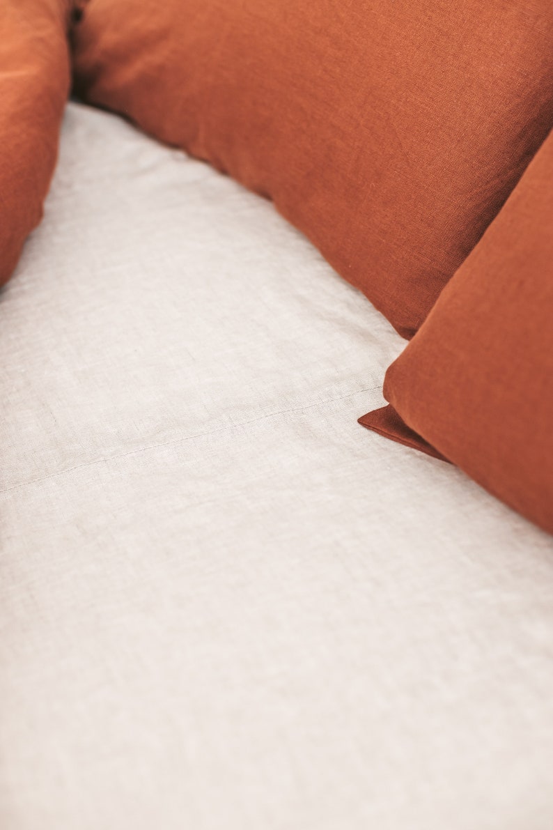 Peut inclure: Deux taies d'oreiller en lin de couleur rouille sur un drap en lin blanc.