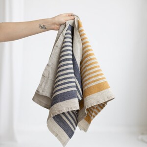 May include: Two linen kitchen towels with striped patterns. One towel has blue stripes and the other has yellow stripes.