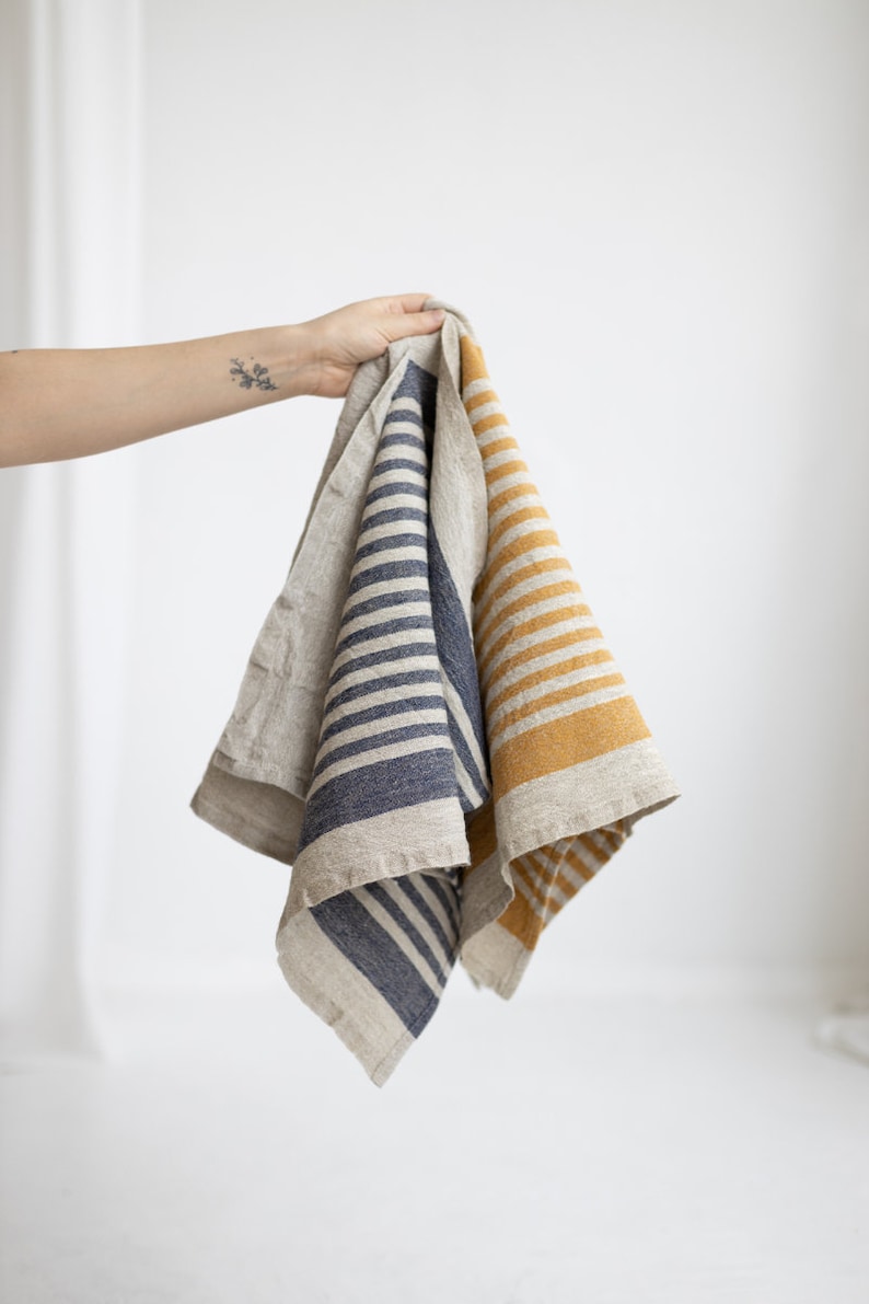 May include: Two linen kitchen towels with striped patterns. One towel has blue stripes and the other has yellow stripes.