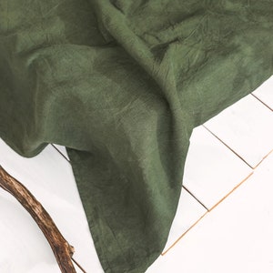 Peut inclure: Un tissu en lin vert fonc&eacute; drap&eacute; sur une surface blanche. Le tissu est froiss&eacute; et a une texture naturelle.
