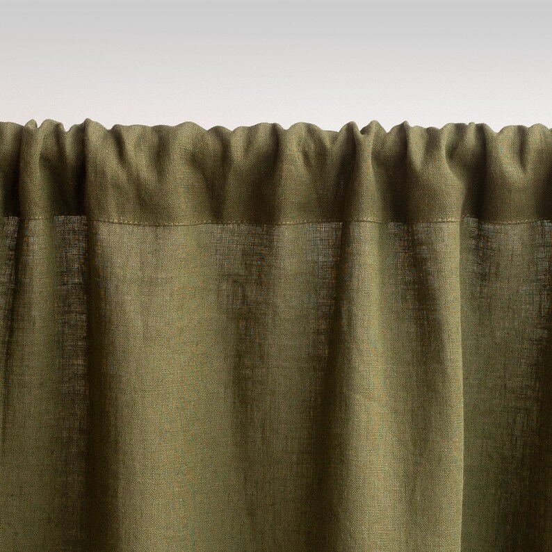 May include: A close-up of a green linen curtain with a subtle texture. The curtain is gathered at the top and hangs in soft folds.
