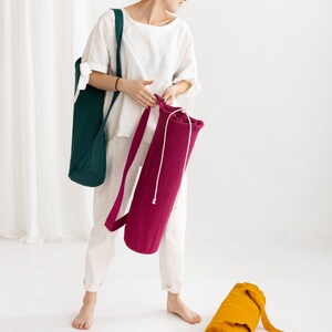 Puede incluir: Dos bolsas para esterillas de yoga, una es de color verde oscuro y la otra de color rosa brillante. Ambas bolsas tienen un cierre de cord&oacute;n y una correa larga.