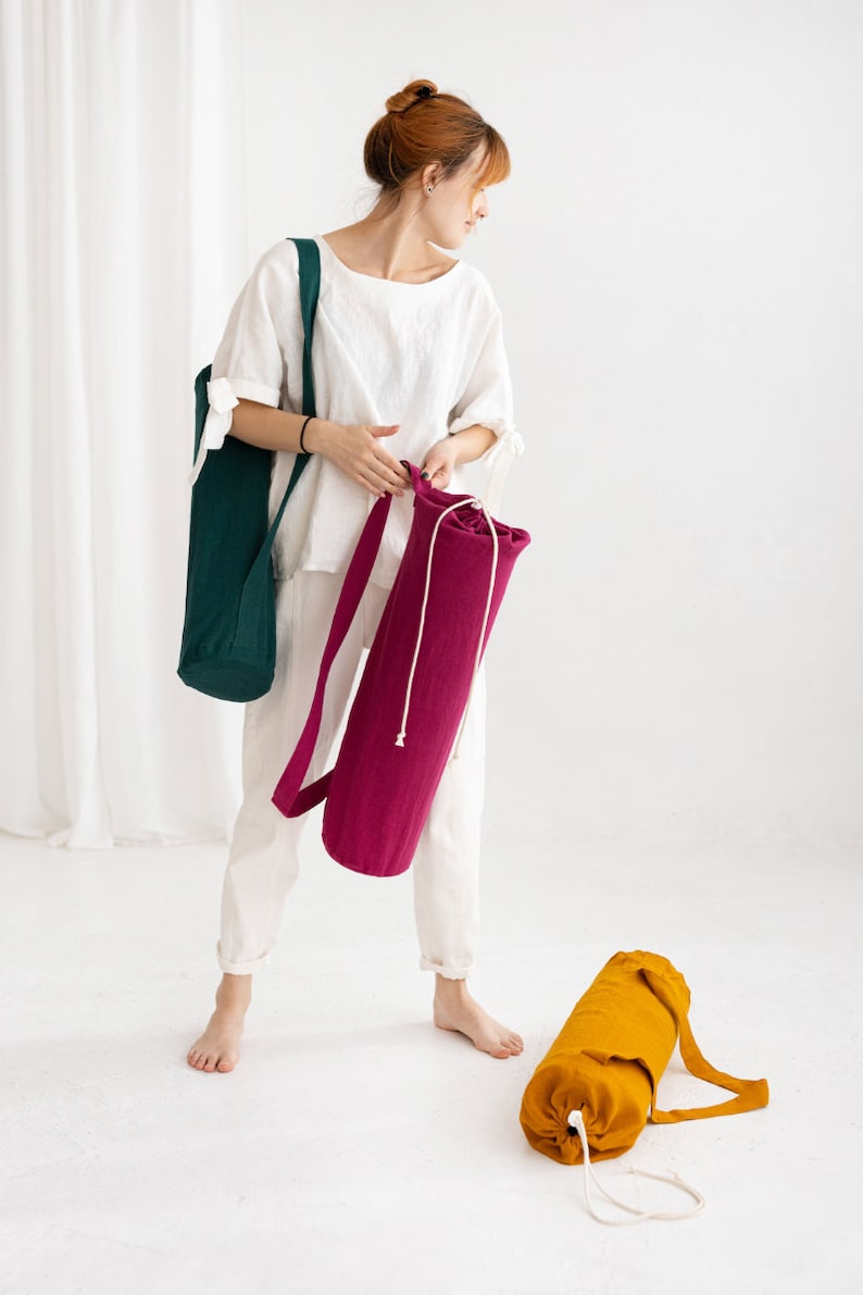 Puede incluir: Dos bolsas para esterillas de yoga, una es de color verde oscuro y la otra de color rosa brillante. Ambas bolsas tienen un cierre de cord&oacute;n y una correa larga.