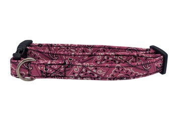 May include: Pink dog collar with a black and white bandana print. The collar has a black plastic buckle and a silver metal D-ring.