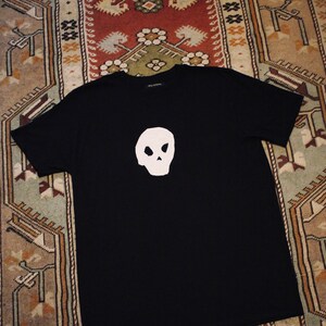 May include: Black t-shirt with a white skull graphic on the front.