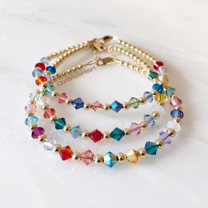 May include: Three gold bracelets with colorful crystal beads. Each bracelet features a different color scheme, with beads in shades of red, blue, green, and yellow.
