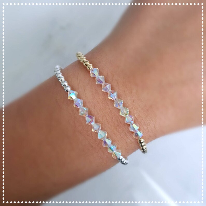 May include: Two bracelets with iridescent crystal beads. One bracelet has silver beads and the other has gold beads.