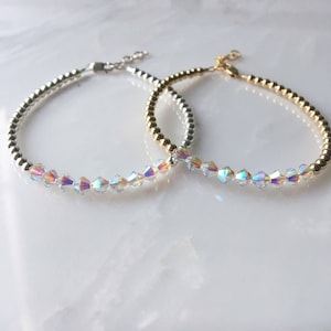 May include: Two delicate bracelets with iridescent crystal beads and silver and gold bead chains.
