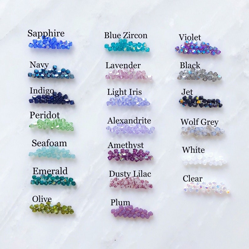 May include: A chart of 18 different colors of beads, each labeled with a color name. The colors include sapphire, blue zircon, violet, navy, lavender, black, indigo, light iris, jet, peridot, alexandrite, wolf grey, seafoam, amethyst, white, emerald, dusty lilac, clear, olive, and plum.
