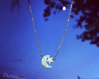 Könnte beinhalten: Eine silberne Kettenkette mit einem Halbmond- und Sternanhänger. Der Mond ist aus weißem Opal und der Stern aus Silber. Die Kette ist vor einem blauen Himmel mit Wolken fotografiert.