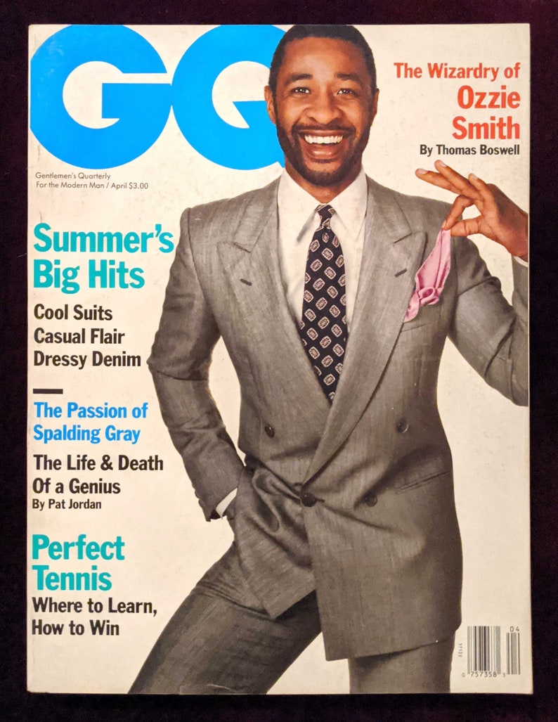 May include: A magazine cover featuring a man in a grey suit with a pink handkerchief in his pocket. The magazine is titled "GQ" and the cover story is "Summer's Big Hits".