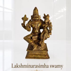 May include: A detailed bronze statue of Lakshminarasimha swamy, depicting a deity with multiple arms and a serene female figure. The statue is on a square base and has intricate details. The text "Lakshminarasimha swamy" is at the bottom.