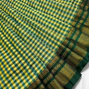 May include: A vibrant textile featuring a checkered pattern in shades of yellow and green. The fabric has a detailed border with gold and green accents. The overall design suggests a traditional or ethnic style.