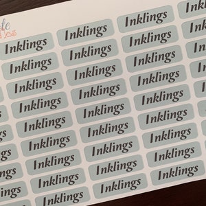 Puede incluir: Una hoja de pegatinas con la palabra "Inklings" repetida varias veces en una fuente cursiva. Las pegatinas son de color azul claro con texto gris oscuro.