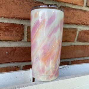 Puede incluir: Un vaso blanco con un dise&ntilde;o marmoleado rosa y naranja y detalles de purpurina.