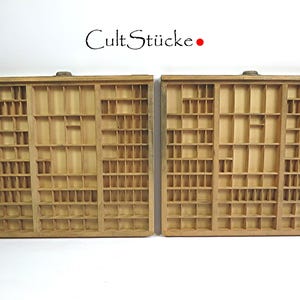 Può includere: Due cassetti in legno per caratteri da stampa con scomparti individuali per riporre i caratteri da stampa. I cassetti sono vuoti e hanno un aspetto usurato e vintage.