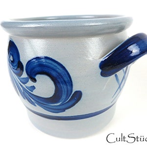 Puede incluir: Una olla de cerámica azul y blanca con un asa azul. La olla tiene un diseño floral y está hecha en un estilo tradicional.