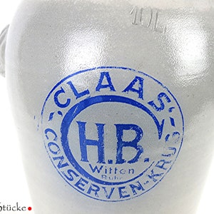 Könnte beinhalten: Eine weiße Keramik-Kanne mit einem blauen Stempel, auf dem "Claas' Conserven-Krus H.B. Witten Ruhr 10L" steht.