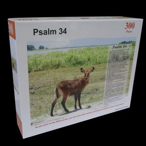 May include: A white puzzle box with the text "Psalm 34" and "300 Pieces." The box features an image of a deer in a grassy field. The text "As you work on this Bible puzzle, you can read, learn and be reminded of valuable truths in God's Word."