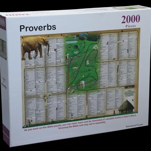 May include: A white box featuring a 2000-piece puzzle with the word "Proverbs" at the top. The puzzle image includes an elephant, a green map, and text from the Bible. The box also has the text: "As you work on this Bible puzzle, you can read, learn and be reminded of valuable truths in God's Word."