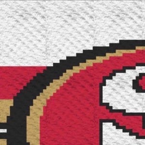 May include: A pixelated graphic design featuring a red circular emblem with a thick black and gold border. The emblem is set against a white background with a horizontal red stripe. The design displays a textured, grid-like pattern throughout.