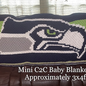 Puede incluir: Manta de bebé de ganchillo hecha a mano con un diseño en azul marino, blanco, gris y verde. La manta muestra una imagen estilizada de un pájaro. Mide aproximadamente 91 cm x 122 cm.