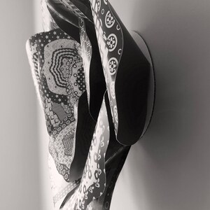 May include: Black and white abstract wall art sculpture made of paper with a variety of patterns. The sculpture is folded and layered to create a three-dimensional effect.