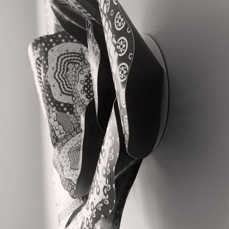 May include: Black and white abstract wall art sculpture made of paper with a variety of patterns. The sculpture is folded and layered to create a three-dimensional effect.