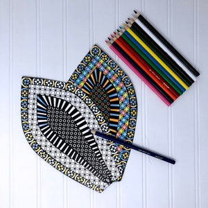 May include: A set of three black and white patterned paper fan shapes with colorful details. The fans are arranged in a heart shape. A set of colored pencils are also included in the image.